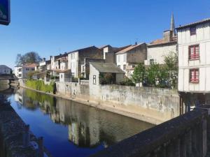 a river in a city with houses and buildings at La maisonnette du marais in Fontaines