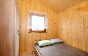 a room with a bed in a wooden room with a window at Domki pod wzgórzem in Kopań
