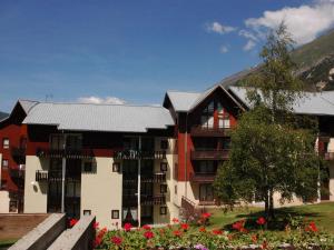 un grand bâtiment avec des fleurs devant lui dans l'établissement Appartement Lanslevillard, 2 pièces, 5 personnes - FR-1-508-215, à Lanslevillard