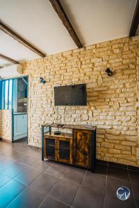 sala de estar con pared de piedra y TV. en APPART T3, en Bagnols-sur-Cèze