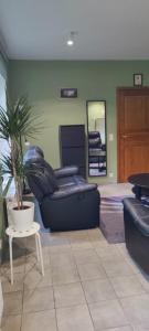 een woonkamer met zwarte lederen meubels en een potplant bij Chez Nous in Bastenaken