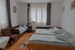 a bedroom with two beds and a chair and a couch at Pensiunea La Maison Verte in Pietroasa