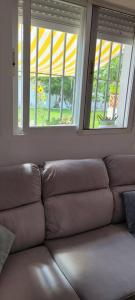 - un canapé dans le salon avec 2 fenêtres dans l'établissement Casa con piscina privada y jardín, à Chiclana de la Frontera