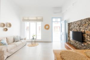 a white living room with a couch and a tv at Helona guesthouse, Skopelos in Skopelos Town