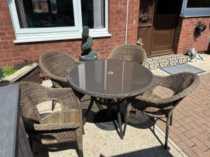 a glass table with four wicker chairs around it at Central Aster House, 3 Bedrooms, Parking in Nottingham