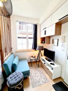 un salon avec un canapé bleu et une télévision dans l'établissement ThémisHouse - Proche Tribunal - Centre - wifi - TV, à Douai