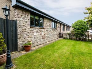 a stone house with a yard with a fence at Polished Pebble in Beadnell