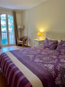サンタ・ウルスラにあるLagos de La Quintaのベッドルーム1室(紫色のベッド1台、椅子、窓付)