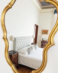 a bedroom with a white bed with a gold framed mirror at Cimabue 9 in Florence