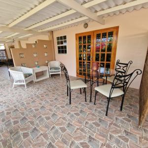 a patio with chairs and a table on a stone floor at Nos Soño Stay and Dive in Westpunt