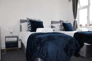1 dormitorio con 2 camas con sábanas azules y ventana en Coventry Cosy Home - Great location for Contractors, Families, Relocators, close Walsgrave Hospital and Motorways, en Wyken