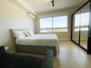 ein Schlafzimmer mit einem Bett und einem großen Fenster in der Unterkunft Studio Connect PUC in Porto Alegre