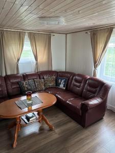 a brown leather couch in a living room with a table at Barents sea window in Ytre Kiberg