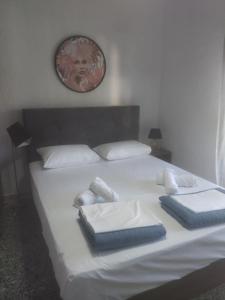 Una cama con sábanas blancas y toallas azules. en PELEKAN rooms and apartments ATHINA 23, en Pefkohori