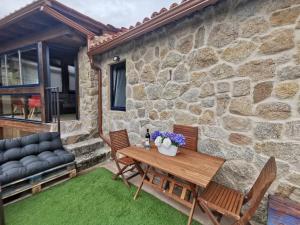 Casa de piedra con mesa de madera y sillas en O Recuncho de Tibias en Pereiro de Aguiar