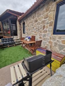 a barbecue grill on a patio with a table at O Recuncho de Tibias in Pereiro de Aguiar