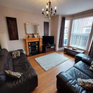 a living room with a leather couch and a television at 3 bed Luxury Victorian Home with Hot Tub in Nottingham