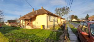 una pequeña casa amarilla al lado de una calle en Öregakác Vendégház, en Tiszaladány