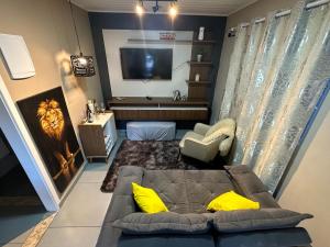 een woonkamer met een bank en een televisie bij Apartamento aconchegante próximo Capivari in Campos do Jordão