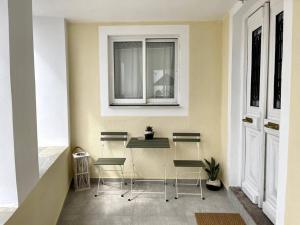 ポロスにあるSunset Havenの椅子3脚、テーブル、窓が備わる客室です。