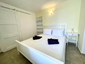 Un dormitorio con una cama blanca con dos bolsas. en Sunset Haven, en Poros