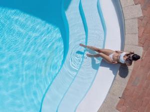 a woman in a swimsuit is going down a swimming pool at Hotel Pedra Santa in Baja Sardinia