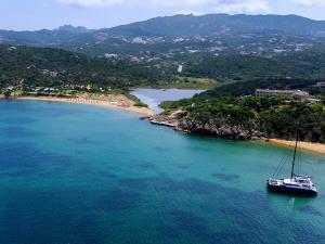 a boat in the water next to a beach at Hotel Pedra Santa in Baja Sardinia +90 photos