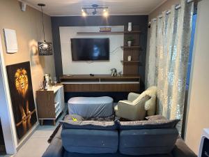 een woonkamer met een blauwe bank en een tv bij Apartamento aconchegante próximo Capivari in Campos do Jordão