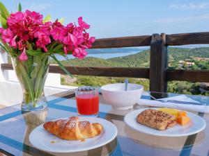 a table with two plates of food and a vase with flowers at Hotel Pedra Santa in Baja Sardinia