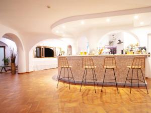 un bar en una habitación con 3 taburetes en Hotel Pedra Santa en Baja Sardinia
