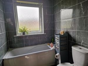 a bathroom with a tub and a window and a toilet at Therence Accommodations can sleep up to 4 Guests in Chesterton, Stoke on Trent in Longport