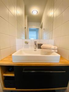 La salle de bains est pourvue d'un lavabo blanc et d'un miroir. dans l'établissement Ferienwohnung Brunnkogelblick, à Neukirchen