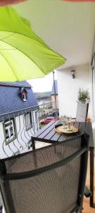 a balcony with a table and a green umbrella at Apartment In Spay Smile Zell-Merl Mosel in Zell an der Mosel