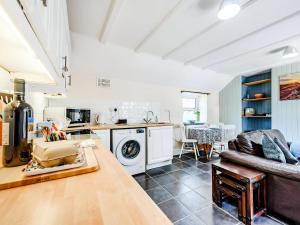a living room with a couch and a kitchen at Studio Cottage in Treffynnon 