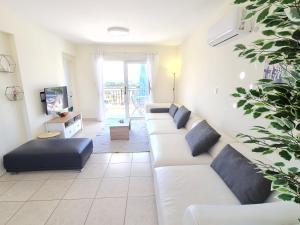uma sala de estar com um sofá branco e almofadas azuis em Stunning views' Apartment with Pool em Pafos