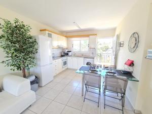 uma cozinha com um frigorífico branco, uma mesa e cadeiras em Stunning views' Apartment with Pool em Pafos