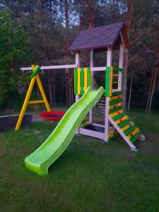 a playground with a slide and a play house at Atpūta pie upītes in Krāslava