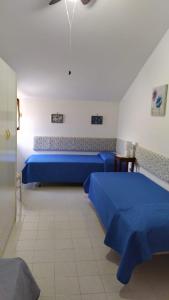 een kamer met twee blauwe bedden in een kamer bij CASA VACANZE ARBORIAMAR SORSO SARDEGNa in Marina di Sorso