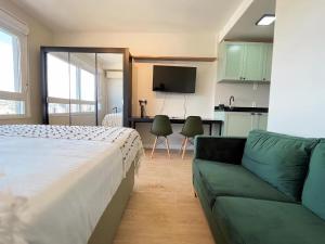 ein Schlafzimmer mit einem Bett und einem Sofa sowie eine Küche in der Unterkunft Studio Connect PUC in Porto Alegre