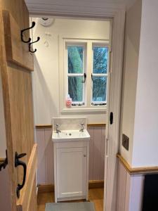 a bathroom with a white sink and two windows at Tranquil Spot Shepherds Hut in Cinderford