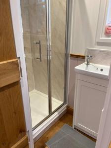 a bathroom with a shower and a sink at Tranquil Spot Shepherds Hut in Cinderford