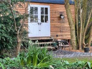 uma cabina de madeira com uma porta branca e um banco em Tranquil Spot Shepherds Hut em Cinderford