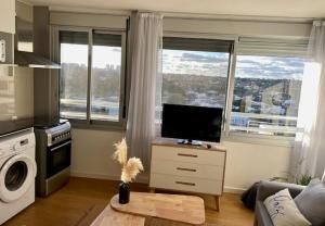 ein Wohnzimmer mit einem TV und 2 Fenstern in der Unterkunft Encantador apartamento en Malvín in Montevideo