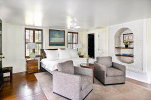 een slaapkamer met een wit bed en 2 stoelen bij Rhett House in Beaufort