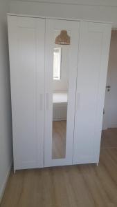 um armário branco com um espelho num quarto em Carcavelos Beach walking distance room in shared apartment em Oeiras