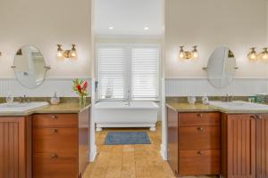 a bathroom with two sinks and a tub and two mirrors at 1730 Kaleka 4 Bed Poipu House, Guest House walk to Beach in Koloa