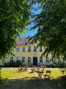 a large white house with picnic tables in front of it at Gut Manderow an der Ostsee in Hohenkirchen