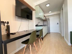 eine Küche mit einem Schreibtisch mit 2 Stühlen und einem TV in der Unterkunft Studio Connect PUC in Porto Alegre
