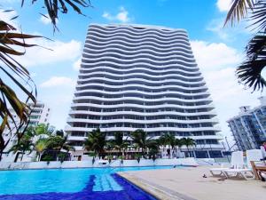 a hotel with a swimming pool in front of a building at Departamento Playero Fountaine Bleau Frente al Mar Tonsupa in Tonsupa