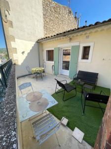 een patio met stoelen en tafels op een huis bij Appartement+Terrasse en Provence dans le Luberon in Apt